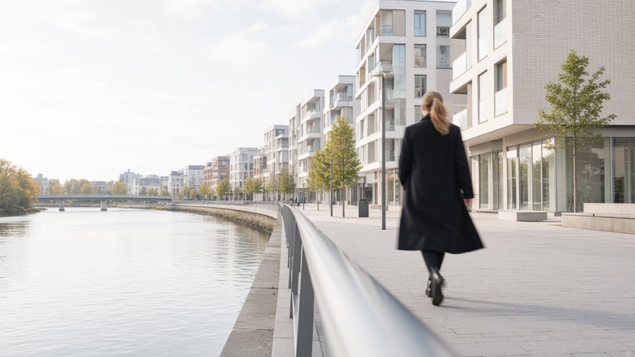 A bright northern European river promenade, a figure walking away